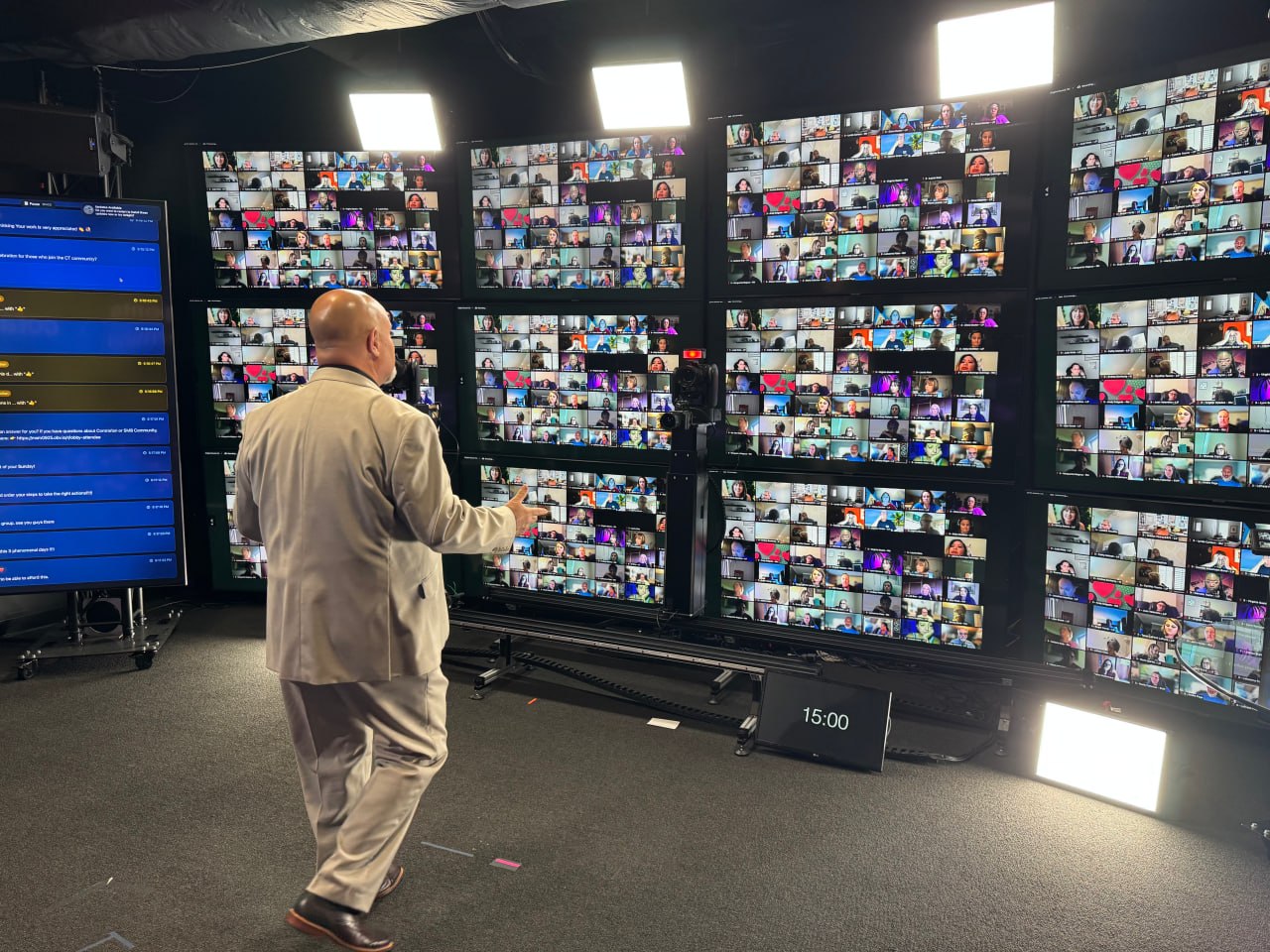 A presenter engaging a large remote audience across a wall of live video screens