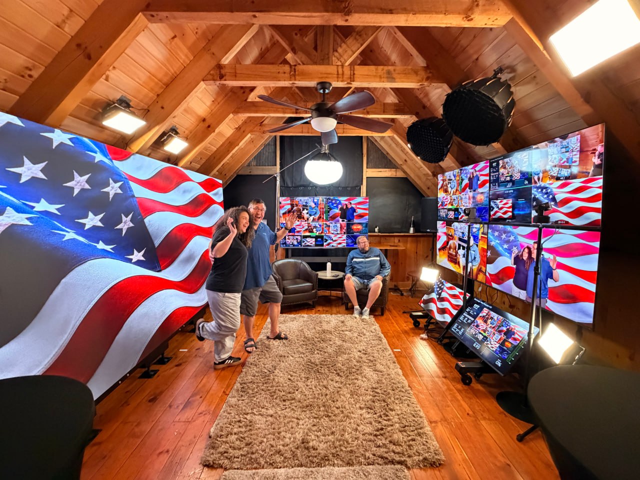 A warm wood-beamed broadcast studio with large LED walls and production monitors